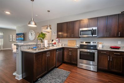 Open layout kitchen with wood style flooring and cabinets