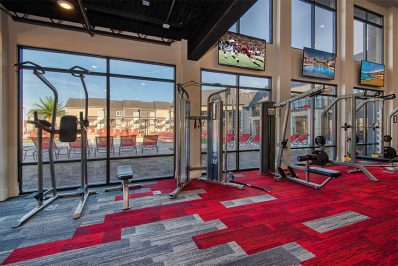 Red carpet and weight machines in fitness center looking out towards pool