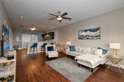 Open layout living room with white sofas and a ceiling fan