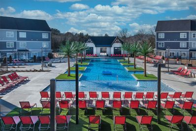 Arial view of resort-style pool with red outdoor pool deck seating