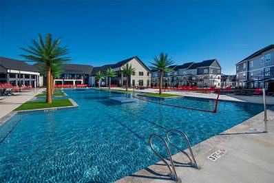 Resort-style pool with trees surrounded by buildings